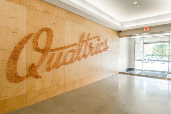 Qualtrics logo on wall - commercial real estate broker Woodley Real Estate