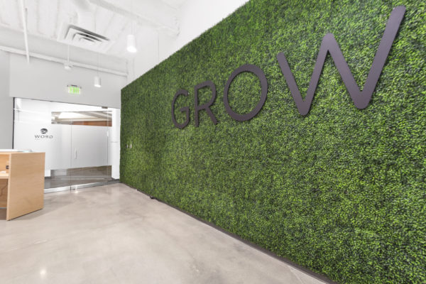 Grow reception area, wall covered in greenery with logo | Utah Commercial Real Estate
