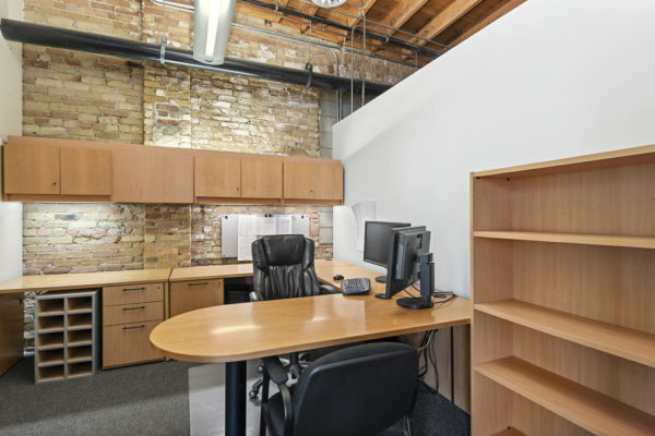 enclosed office with exposed brick wall, nice desk and chair